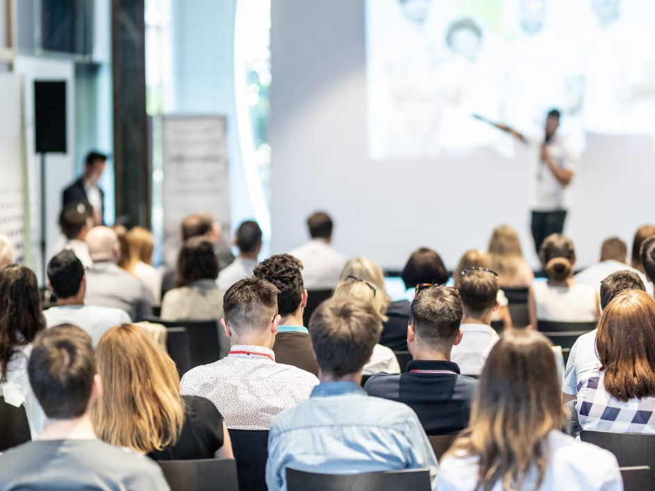 A crowd of professionals listening to a presenter.